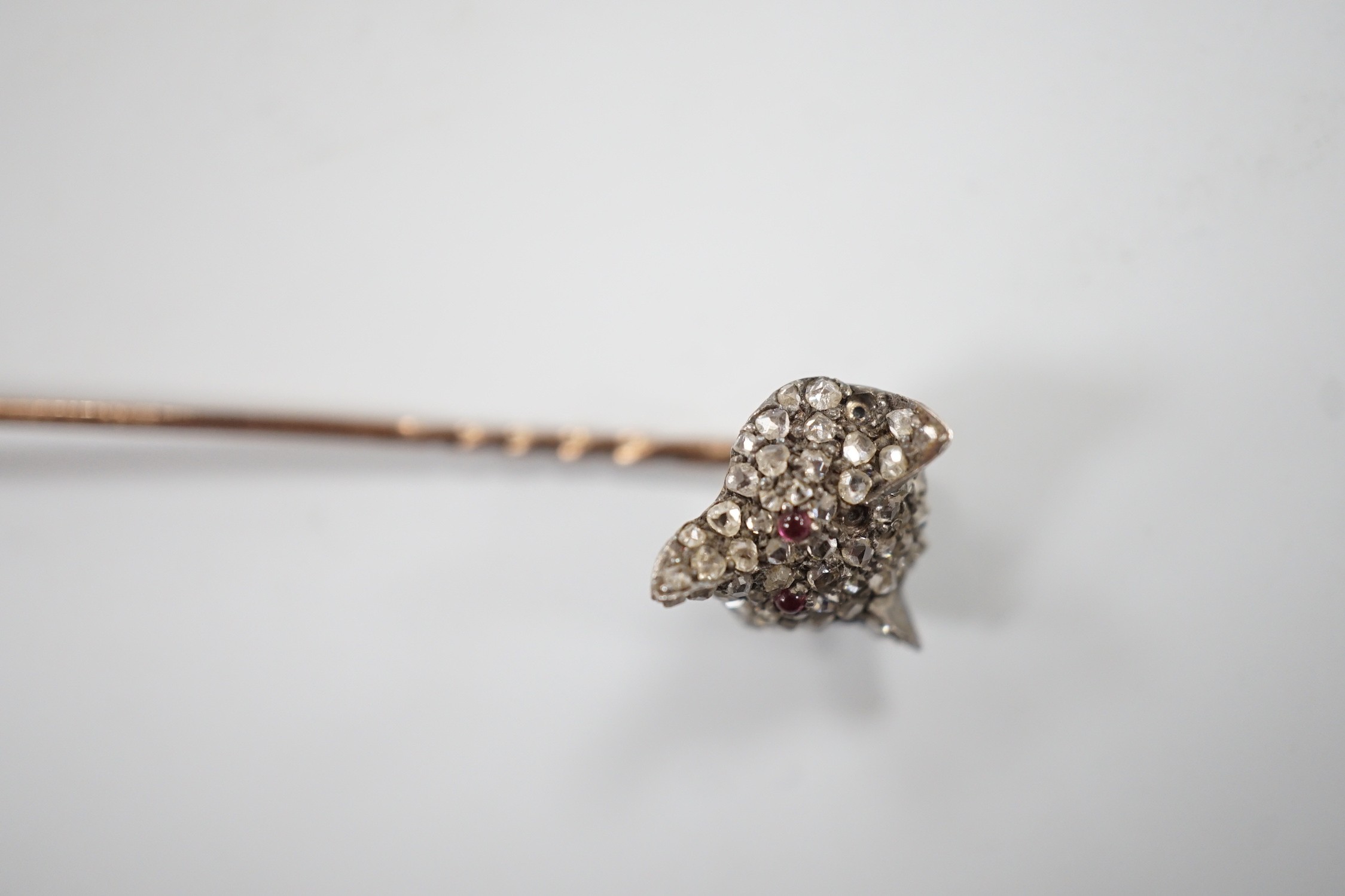 A late Victorian yellow and white metal, cabochon ruby? and rose cut diamond set fox head stick pin, 56mm, gross weight 4.7 grams (two stones missing).